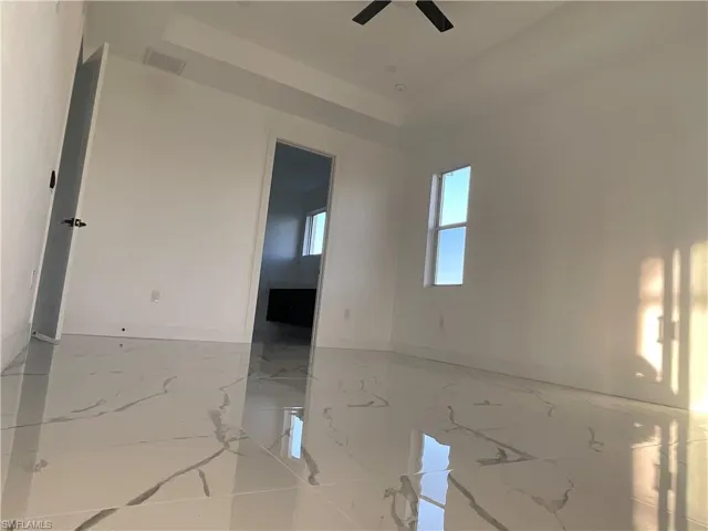 Unfurnished room featuring a tray ceiling and ceiling fan