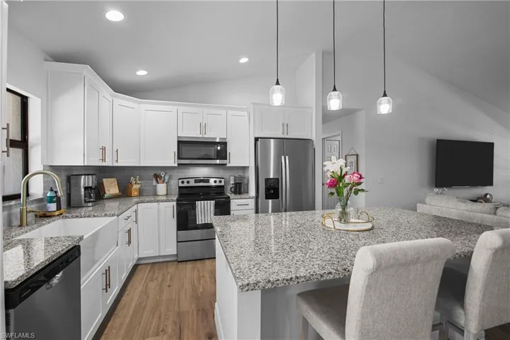 kitchen with oversized island, farmhouse sink, soft-close cabinets, and stainless steel appliances