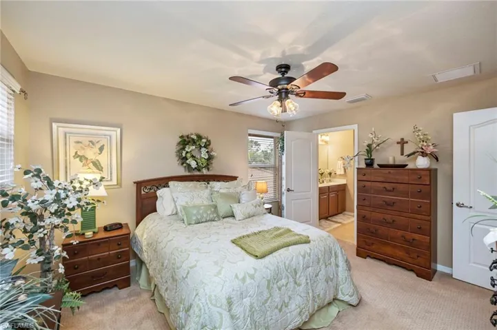 Bedroom with light colored carpet, ceiling fan, and ensuite bath