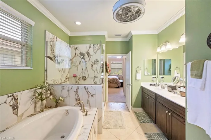 Bathroom with vanity, a garden tub, a marble finish shower, ensuite bath, and crown molding