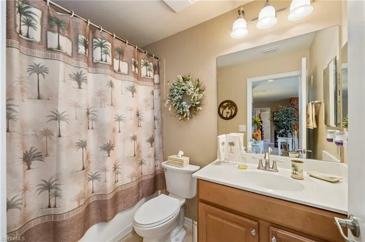 Full bath featuring vanity, shower / bath combo with shower curtain, and a textured wall