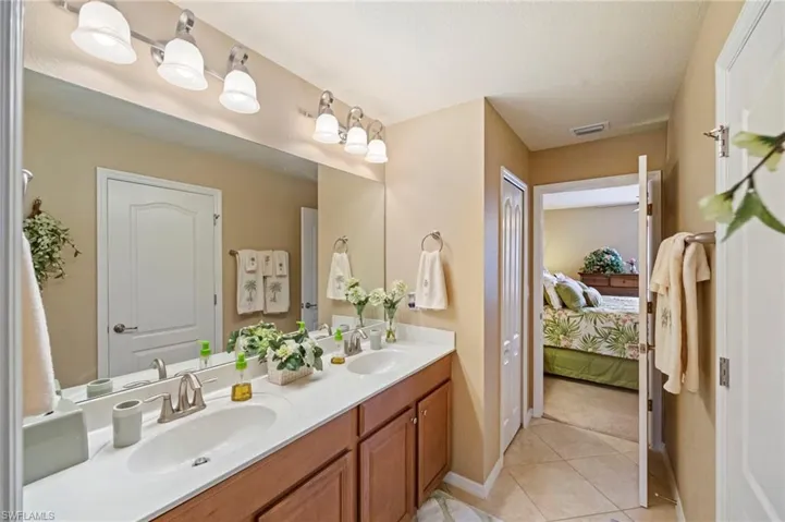 Ensuite bathroom with double vanity and light tile patterned flooring
