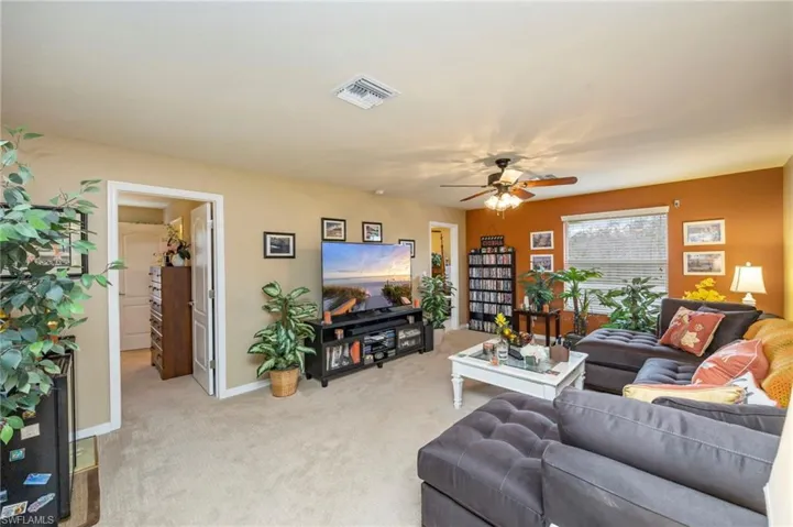 Living area with light colored carpet and a ceiling fan
