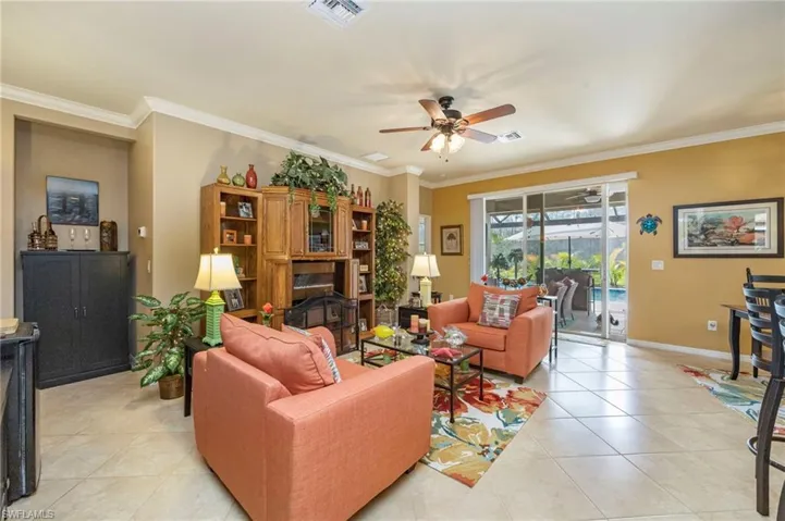 Living area with crown molding, light tile patterned flooring, and ceiling fan