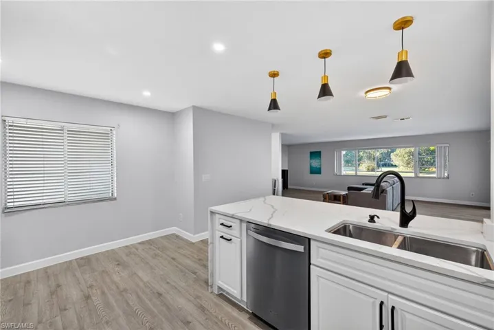 Kitchen island featuring a quartz countertop, undermount double-basin sink, and matte black faucet