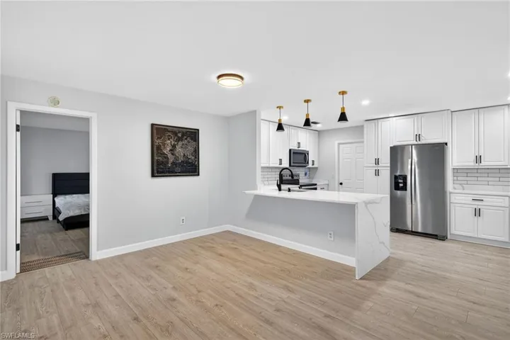 Open concept living area featuring wood-finish flooring, white walls, and a modern kitchen
