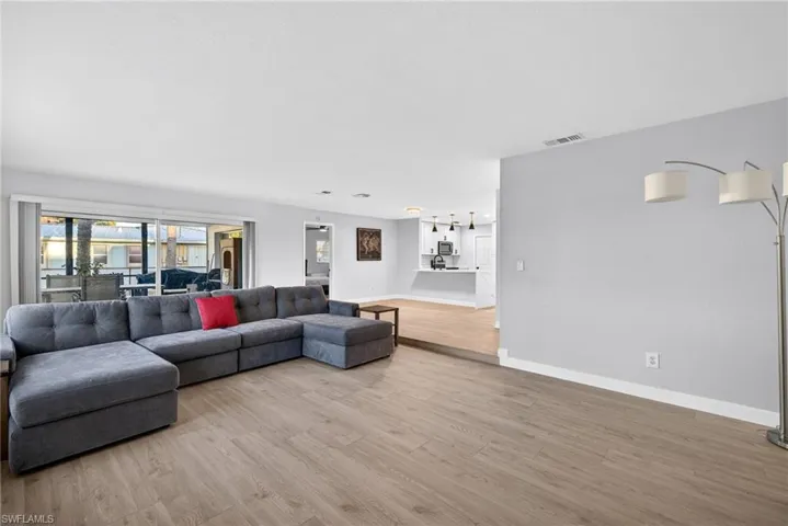 Spacious living area featuring wood-finish flooring, light-toned wall paint, and recessed ceiling lighting