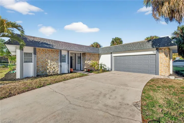 Exterior featuring a gray asphalt shingle roof, stone facade accents, a concrete driveway, and an attached garage with a panel-style door