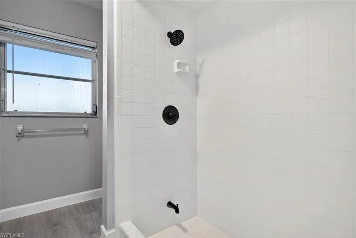 Shower with subway tile surround, matte black fixtures, and built-in soap dish