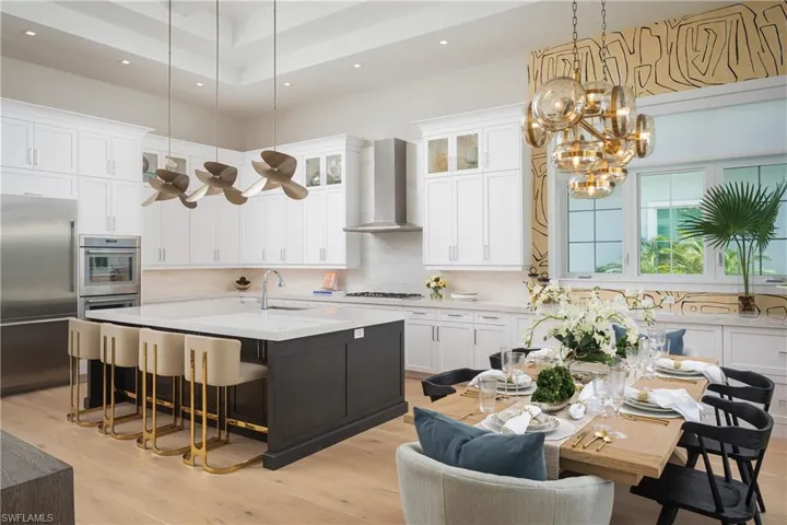 Kitchen featuring an island with sink, wall chimney exhaust hood, light hardwood / wood-style flooring, and white cabinetry