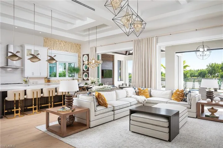 Living room with a raised ceiling, light hardwood / wood-style floors, and an inviting chandelier