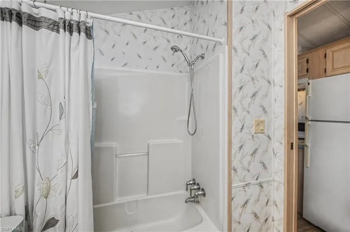 Bathroom featuring wallpapered walls and shower / tub combo