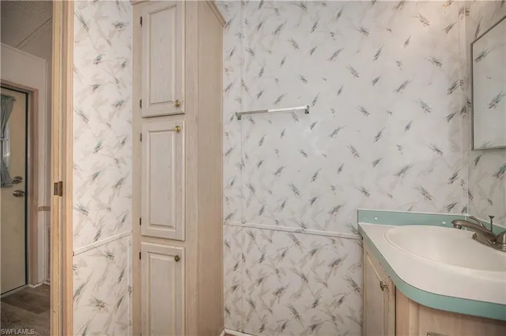 Bathroom with wallpapered walls and vanity