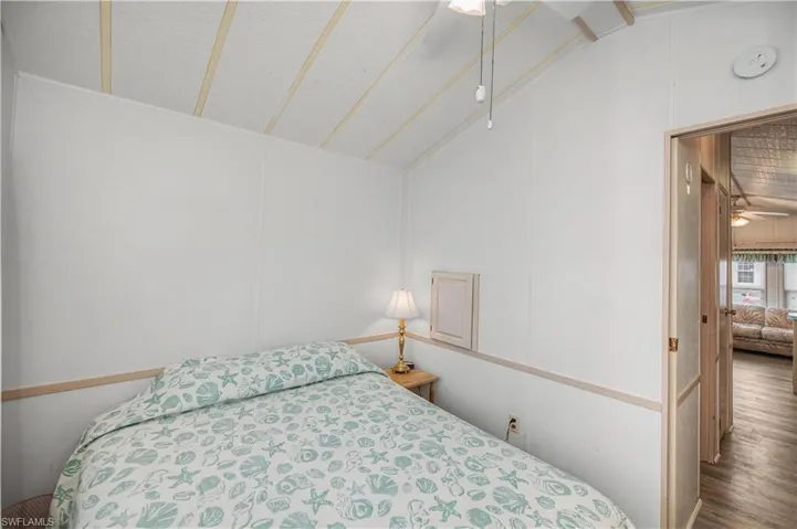 Bedroom with a decorative wall and vaulted ceiling
