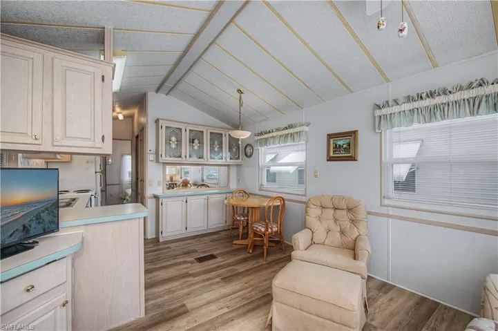 Sitting room with light wood-type flooring and vaulted ceiling with beams