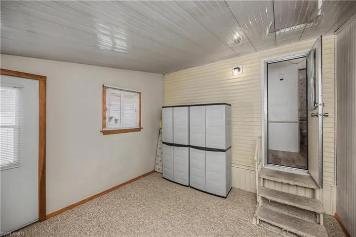Unfurnished bedroom with wooden walls, light carpet, and a closet