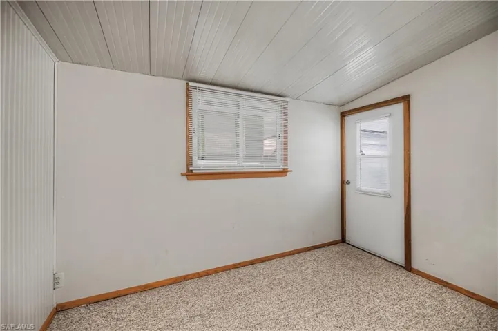 Empty room featuring vaulted ceiling and light colored carpet