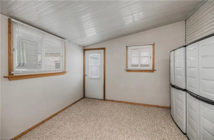 Unfurnished bedroom with lofted ceiling and light carpet