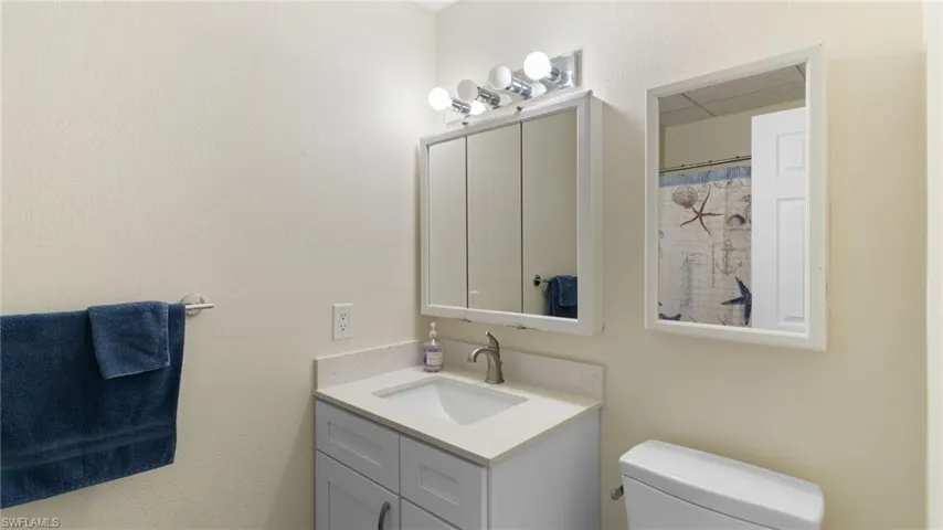 Full bathroom with a shower with curtain, vanity, and a textured wall