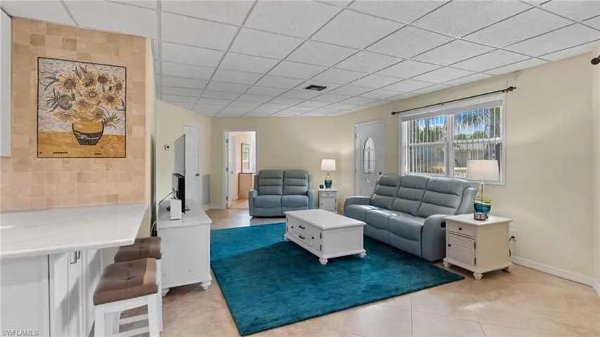 Living room featuring light tile patterned floors and a drop ceiling