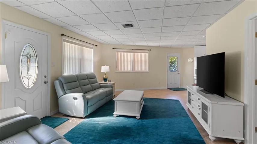 Tiled living area featuring a drop ceiling and baseboards