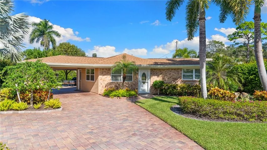 Single story, ranch-style home featuring an attached carport, a front lawn, brick siding, and decorative driveway