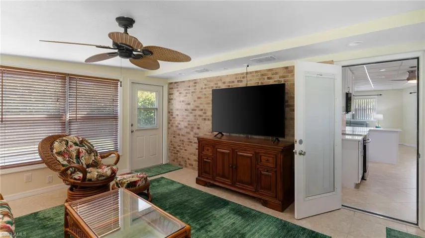 Living room featuring a ceiling fan and brick wall