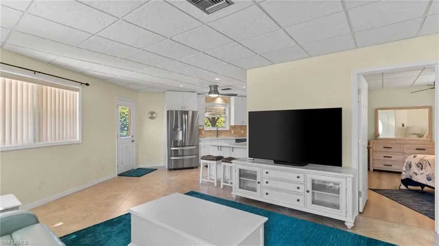 Living area with ceiling fan, light tile patterned flooring, and a paneled ceiling
