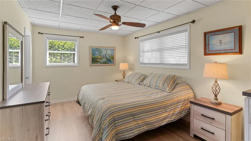 Bedroom with a paneled ceiling, multiple windows, a ceiling fan, and light wood-type flooring
