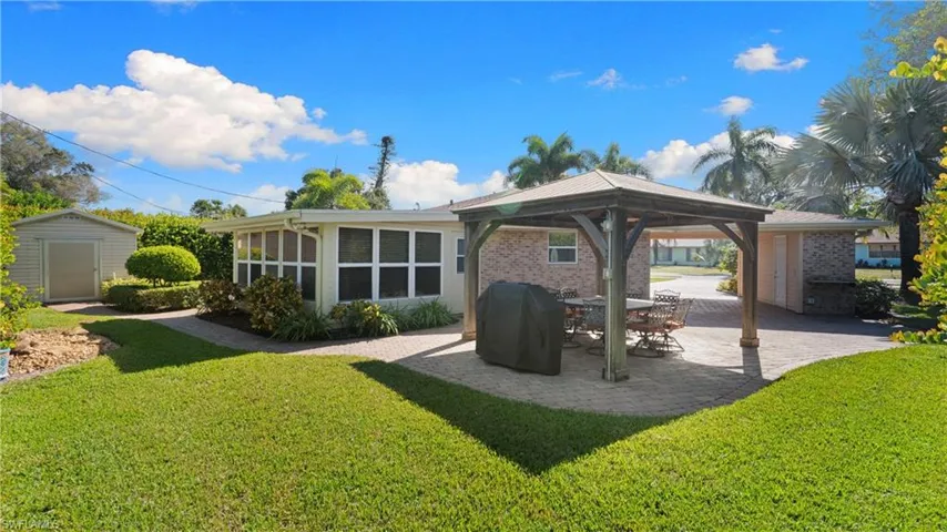 Rear view of property with a gazebo, a lawn, a patio area, and brick siding