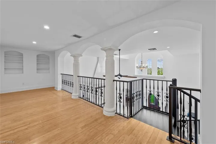Corridor with a chandelier, wood-type flooring, and built in shelves