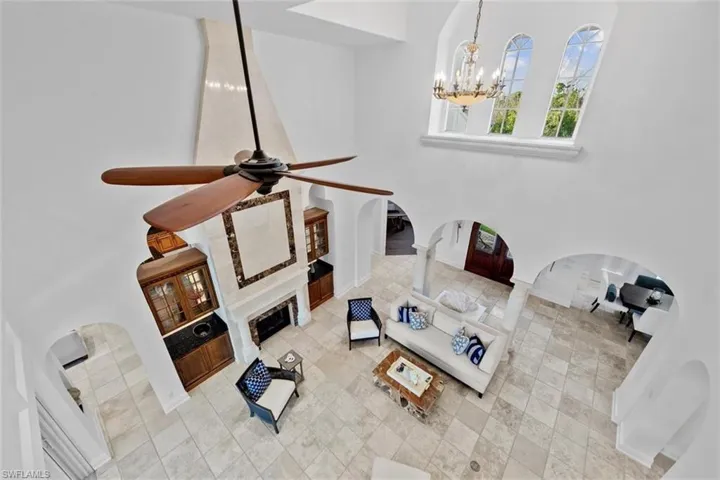 Living room featuring ornate columns and ceiling fan with notable chandelier