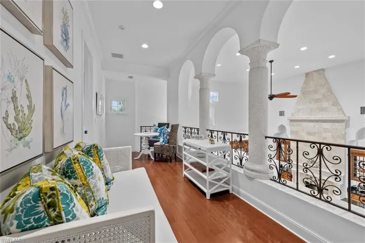 Corridor featuring crown molding, decorative columns, and wood-type flooring