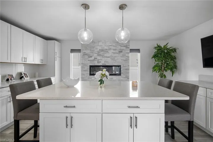 Kitchen with white cabinetry, a kitchen breakfast bar, light hardwood / wood-style floors, and hanging light fixtures