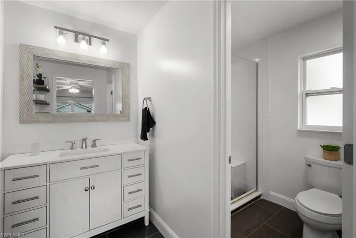 Bathroom featuring vanity, walk in shower, tile patterned floors, and toilet