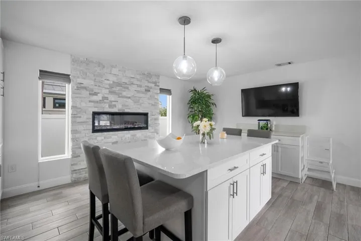 Kitchen featuring a kitchen bar, decorative light fixtures, light hardwood / wood-style flooring, a kitchen island, and white cabinets