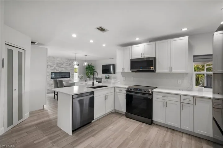 Kitchen featuring white cabinets, kitchen peninsula, stainless steel appliances, and sink