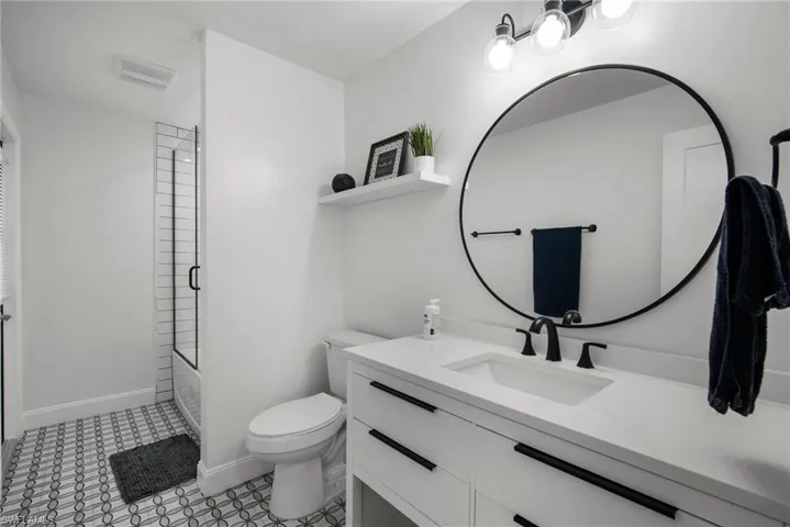 Full bathroom with toilet, combined bath / shower with glass door, and vanity
