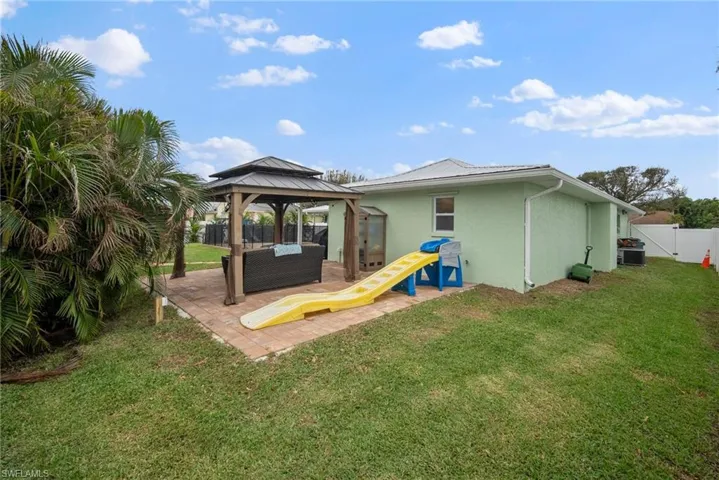 Rear view of property featuring a patio, central AC, a yard, and a gazebo