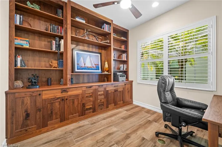 A stunning custom-built office with rich wood cabinetry and serene natural light.