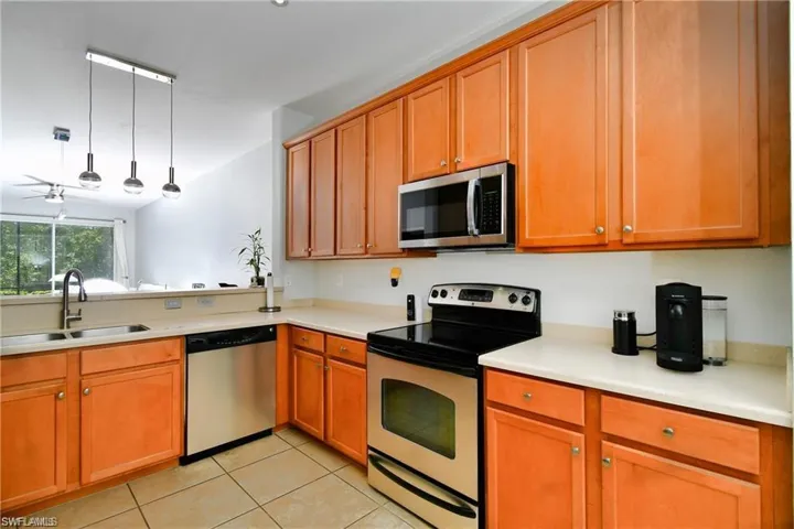 Kitchen featuring pendant lighting, appliances with stainless steel finishes, sink, ceiling fan, and light tile patterned flooring