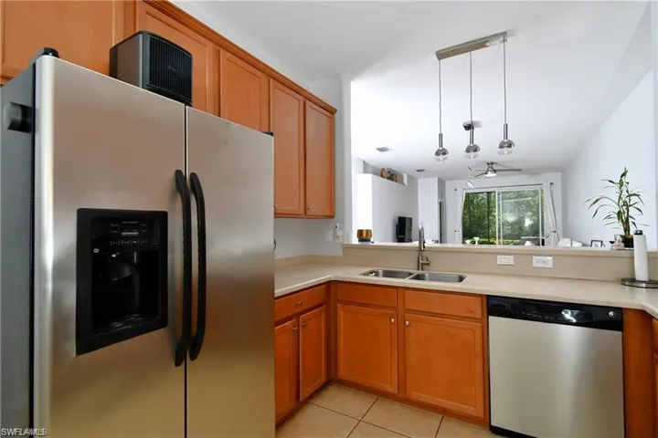 Kitchen featuring stainless steel appliances, sink, kitchen peninsula, light tile patterned flooring, and pendant lighting