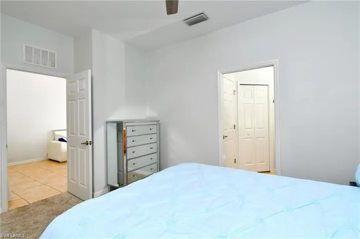 Tiled bedroom with ceiling fan and a closet