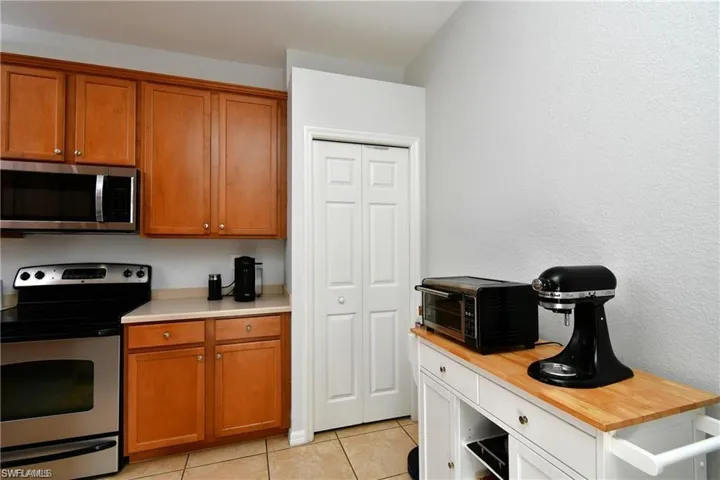 Kitchen with wooden counters, appliances with stainless steel finishes, and light tile patterned flooring