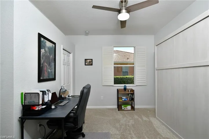 Carpeted home office featuring ceiling fan and a textured ceiling