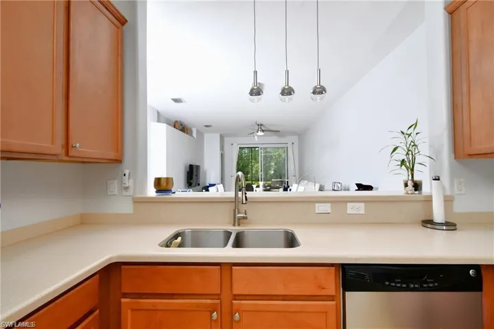 Kitchen featuring hanging light fixtures, dishwasher, vaulted ceiling, sink, and ceiling fan