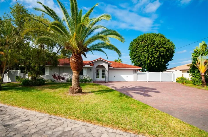 Mediterranean / spanish-style house featuring decorative driveway, an attached garage, a tiled roof, stucco siding, and a gate