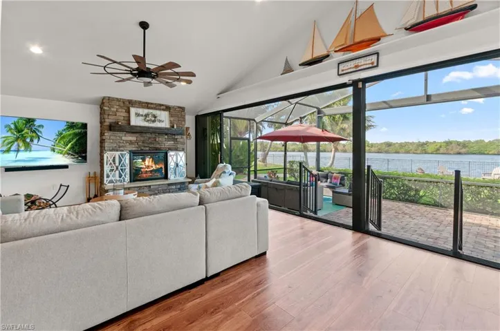 Living room with a sunroom, light wood-style floors, a water view, ceiling fan, and a fireplace