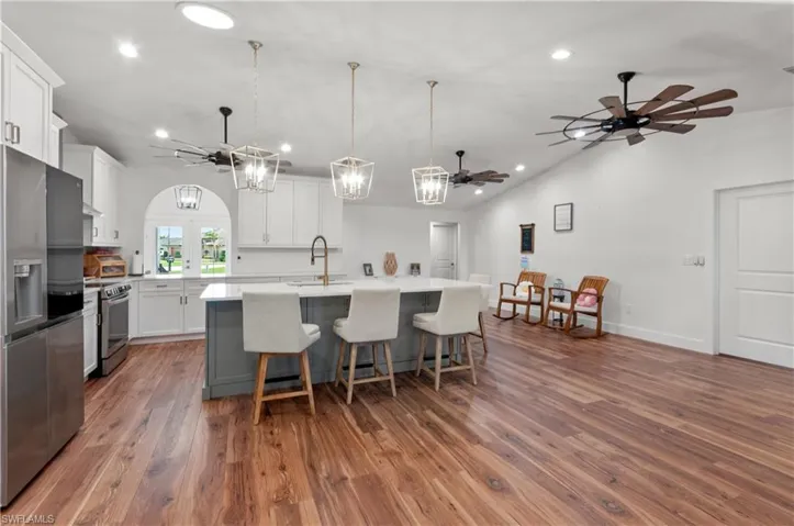 Kitchen with a chandelier, ceiling fan, appliances with stainless steel finishes, gray cabinets, and lofted ceiling