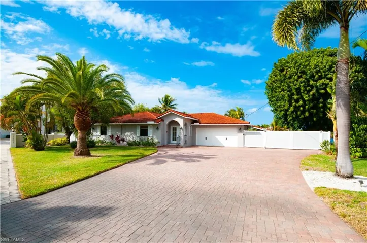 Mediterranean / spanish-style house with an attached garage, decorative driveway, stucco siding, and a gate